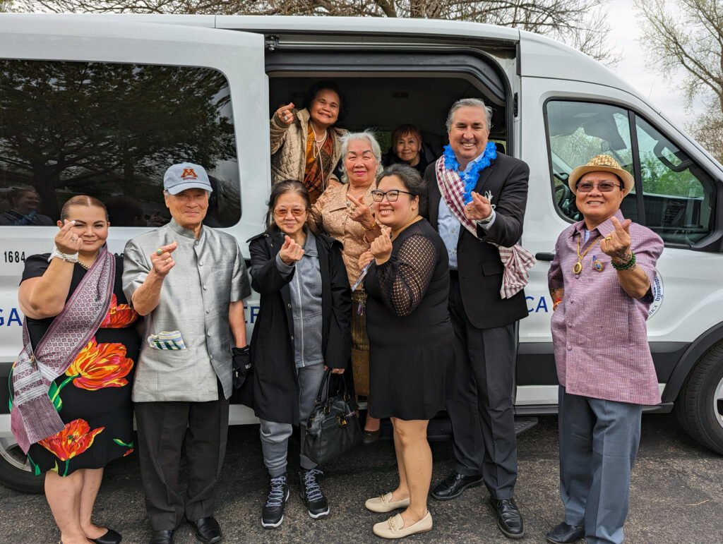 Seniors dressed in Asian-themed celebratory clothing leaving for an event posing outside a van.